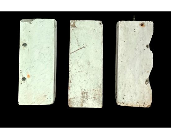 Three architectural elements in marble with a white frame and a variegated red central section.