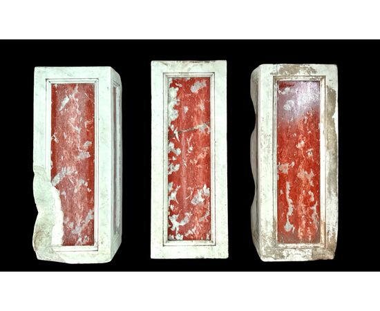 Three architectural elements in marble with a white frame and a variegated red central section.
