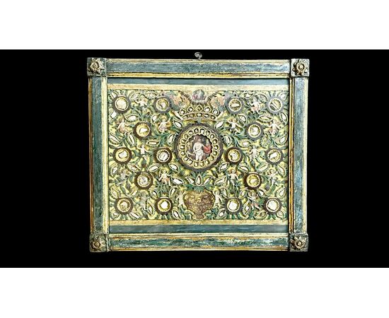 Quadro reliquiario con composizione in legno traforato in rilievo con putti e motivi vegetali. Quadro reliquiario con composizione in legno traforato in rilievo con putti e motivi vegetali.