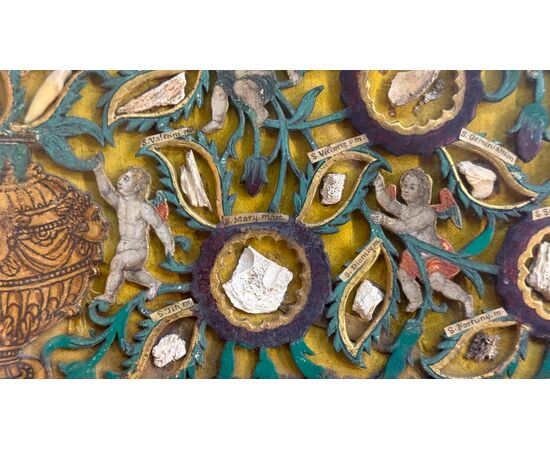 Quadro reliquiario con composizione in legno traforato in rilievo con putti e motivi vegetali. Quadro reliquiario con composizione in legno traforato in rilievo con putti e motivi vegetali.