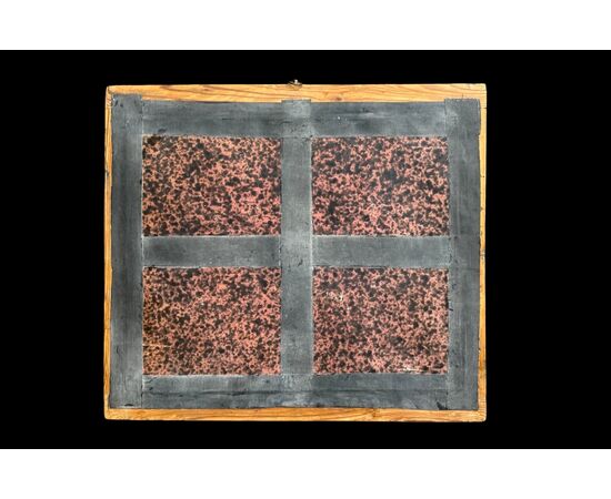 Quadro reliquiario con composizione in legno traforato in rilievo con putti e motivi vegetali.