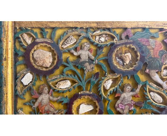 Reliquary painting with openwork wood composition in relief with putti and vegetal motifs. Reliquary painting with openwork wood composition in relief with putti and vegetal motifs.