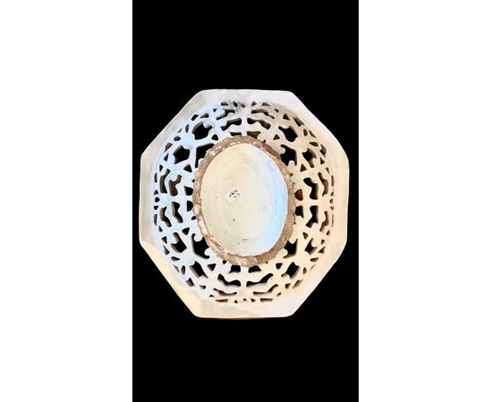 Octagonal raised plate in pierced majolica with geometric motifs and architectural scene in the center. Savona.