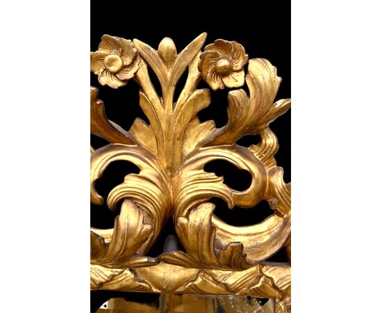 Carved and gilded wooden frame-mirror with 'cartoccio' decoration.