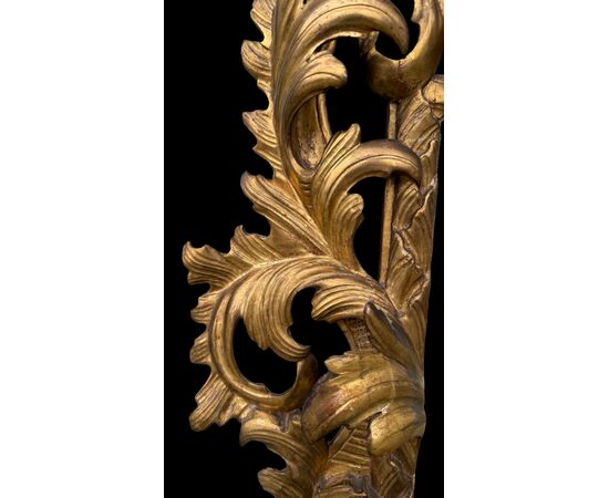 Carved and gilded wooden frame-mirror with 'cartoccio' decoration.