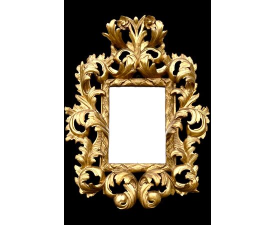 Carved and gilded wooden frame-mirror with 'cartoccio' decoration.