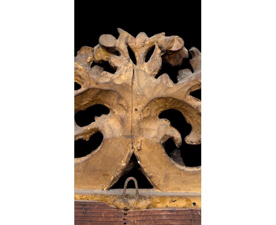 Carved and gilded wooden frame-mirror with 'cartoccio' decoration.