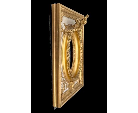 Cornice in legno intagliato con trofei,ghirlande,motivi vegetali e geometrici.