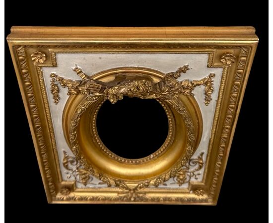 Cornice in legno intagliato con trofei,ghirlande,motivi vegetali e geometrici.