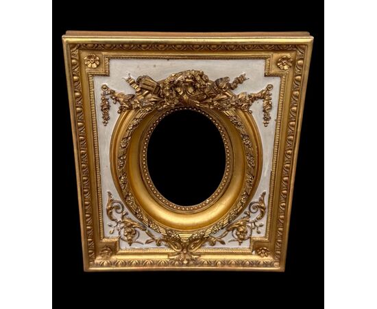 Cornice in legno intagliato con trofei,ghirlande,motivi vegetali e geometrici.