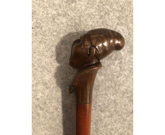 Stick with wooden knob depicting screaming male figure.     