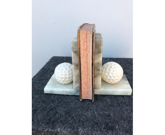 Coppia di fermalibri in alabastro raffiguranti palline da golf.