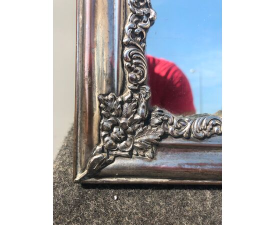 Cornice specchiera in rame argentato con decoro in argento a motivi rocaille.