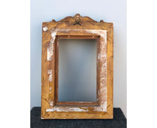 Frame in carved wood and gold leaf with plant and geometric motifs engravings and upper rocaille shield.     