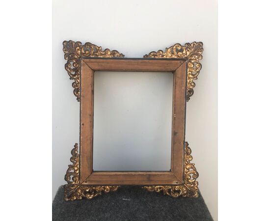 Carved and ebonized wooden frame with rocaille brass details at the corners.     