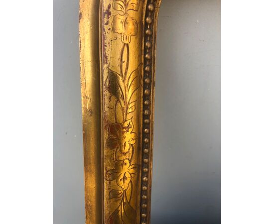 Cornice in legno intagliato e foglia oro con motivi floreali.