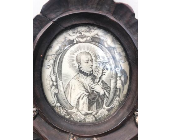 Cornice a doppia faccia in legno intagliato con dettagli in argento e cimasa con stampa e dipinto su vetro raffigurante San Luigi Gonzaga.