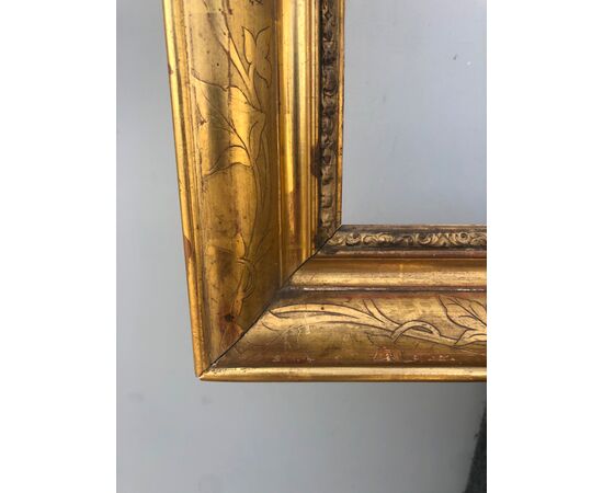 Frame in carved wood and gold leaf with engraved plant motifs.     