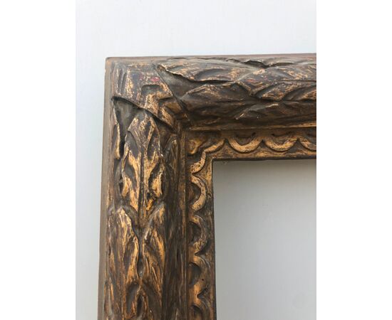 Carved and gilded wooden frame with plant motifs in relief.     