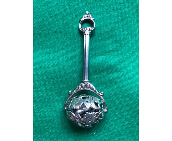 Baby rattle in embossed and perforated silver with stylized floral motifs.     