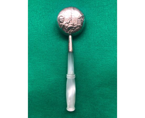 Baby rattle in silver with scene of Baby Jesus and protector Angel. Mother of pearl handle.     
