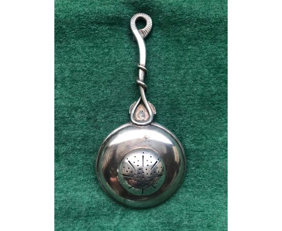 Silver tea strainer with neoclassical mask and snake.     