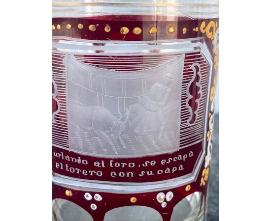 Bicchiere in vetro incamiciato e molato con dettagli smaltati e scena di corrida incisa.Boemia.