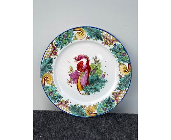 Majolica plate with oriental style decoration with tobacco leaves and rocaille motifs on the brim and bird in the wire.Manufactured by Felice Clerici.Milan.     