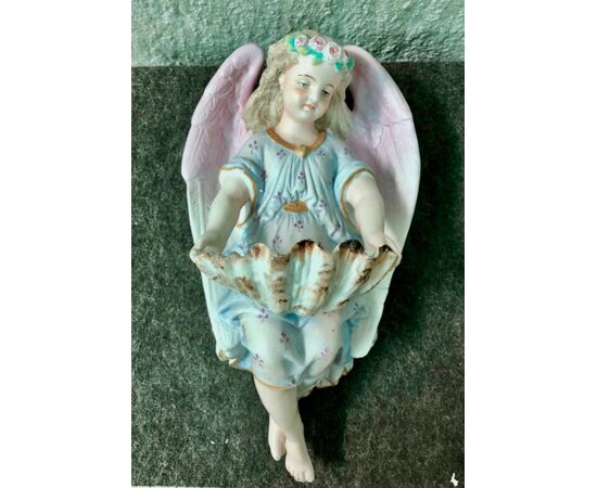 Acquasantiera  in porcellana bisquit raffigurante angelo con corona di fiori che regge la coppa a forma di conchiglia.Francia.