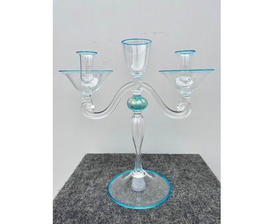 Candeliere in vetro trasparente leggermente iridato con dettagli azzurri.Presenta  forma umana stilizzata a due bracci.Manifattura Seguso.Murano.