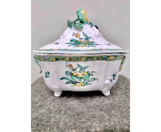 Tureen in majolica with lateral grips in the shape of twigs, rocaille motifs in paste and decoration with floral and vegetable motifs. Fruit-shaped socket. Sannita earthenware.     