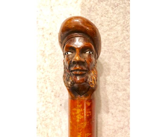 Stick with wooden knob representing a male figure with sideburns and hat.     