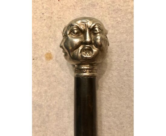 Stick with metal knob depicting 4 grotesque faces. Ebony horn.     