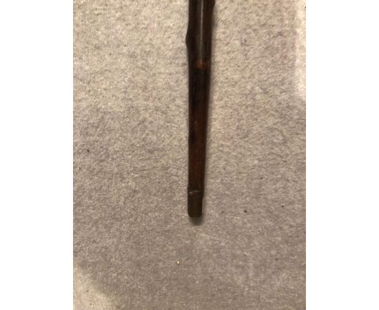 Stick in a single piece made of ebonized fruit wood with a knob representing a grotesque head.     