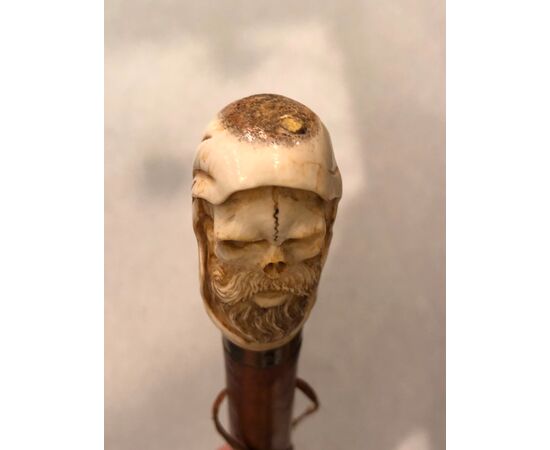 Bastone con pomolo in osso raffigurante teschio con cappuccio e barba.