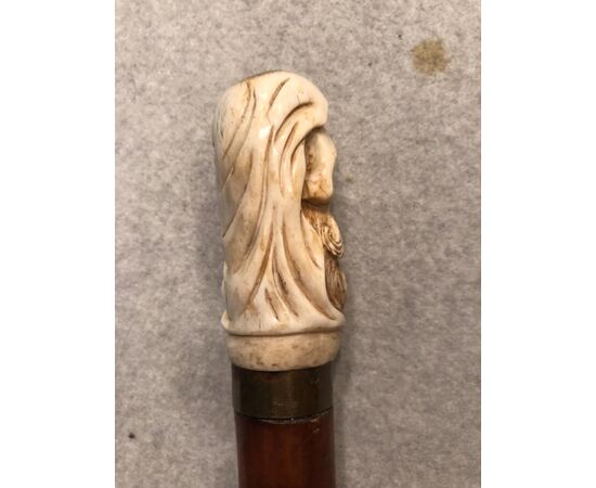 Stick with bone knob depicting skull with hood and beard.     