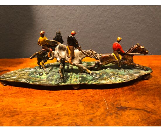Scultura in bronzo raffigurante gruppo di personaggi a cavallo.