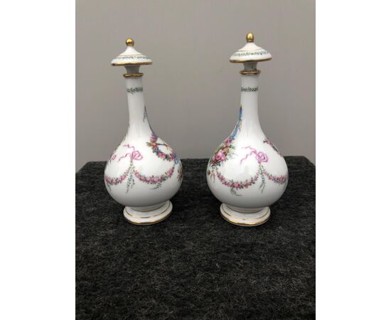 Pair of porcelain perfume bottles decorated with flowers and trophies. France.     