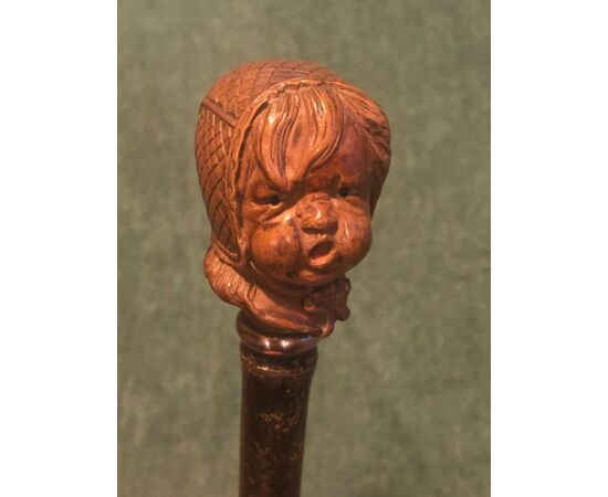 Stick with wooden knob depicting a crying baby&#39;s head.     
