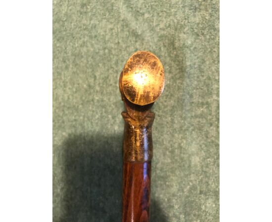 Defense stick with bronze knob depicting the head of a grotesque male figure.     