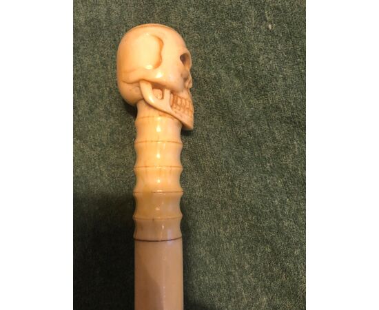 All ivory stick made up of segments. Knob depicting a skull.     