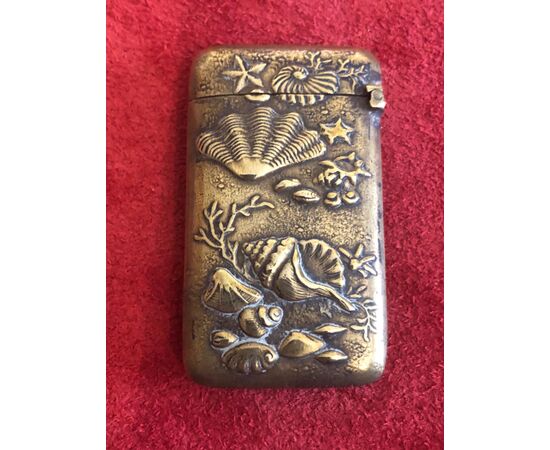 Brass matchbox depicting seashells and marine fauna and flora.     