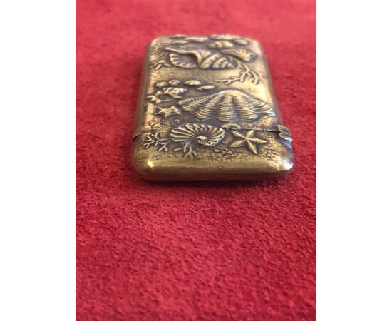 Brass matchbox depicting seashells and marine fauna and flora.     