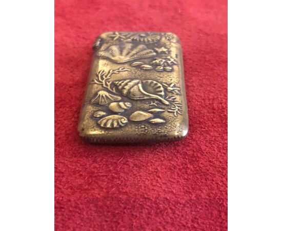 Brass matchbox depicting seashells and marine fauna and flora.     