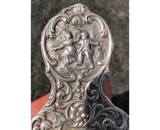 Colino in argento decorato con personaggi popolari e motivi vegetali stilizzati.Olanda.