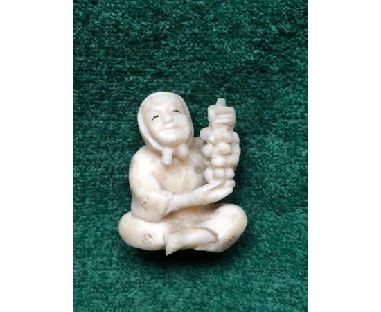 Ivory netsuke &#39;with character sitting with bunch of grapes. Japan.     