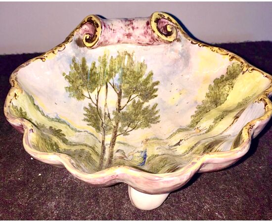 Centerpiece in majolica on three feet in the shape of a shell decorated with characters on a rural background.Manifattura di Angelo Minghetti.Bologna.     