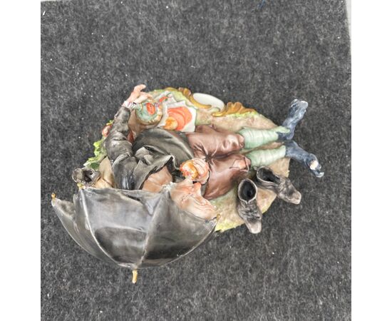 Scultura in porcellana policroma raffigurante personaggio caricaturale con ombrello e cibarie.Giuseppe Cappe’