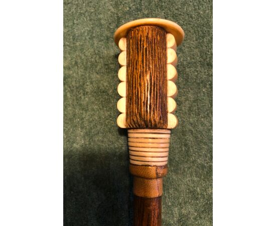 Stick with knob in wood and bone with head of a stylized female figure in art deco style.     