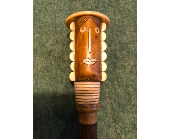 Stick with knob in wood and bone with head of a stylized female figure in art deco style.     